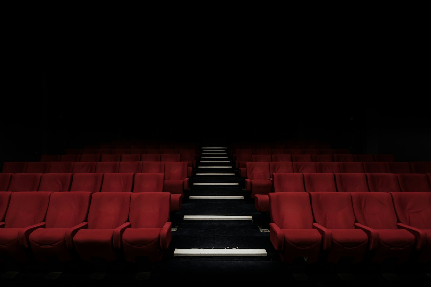 Empty rows of red cinema seats in a darkened auditorium